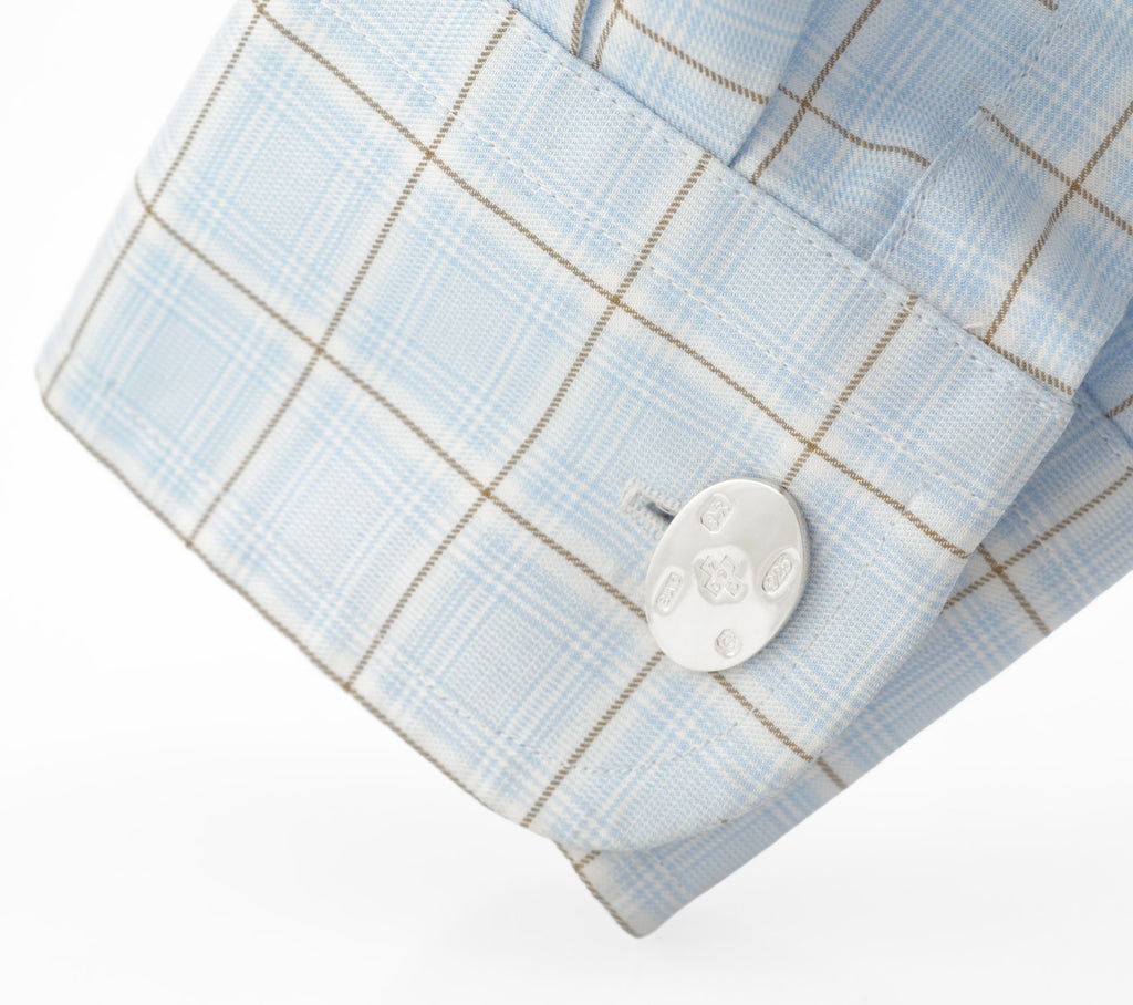 Sterling silver cufflink displayed through a shirt cuff, showing the hallmark front
