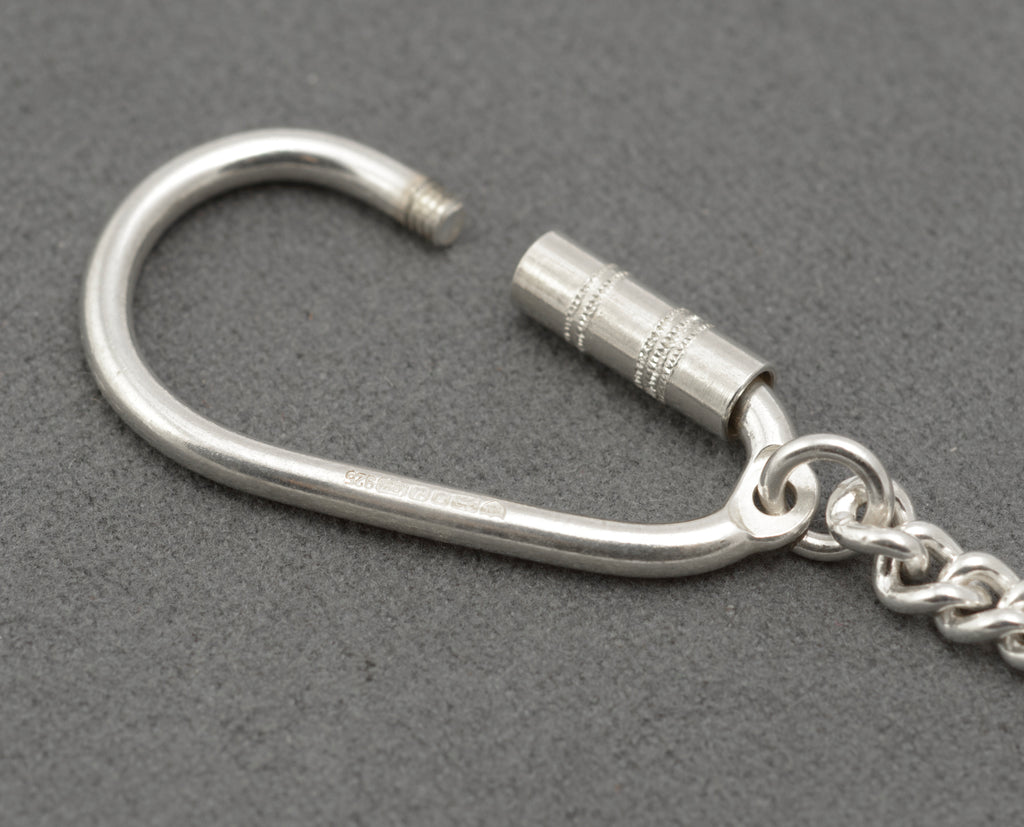 Silver key holder with the screw barrel undone, showing the threaded opening for adding keys
