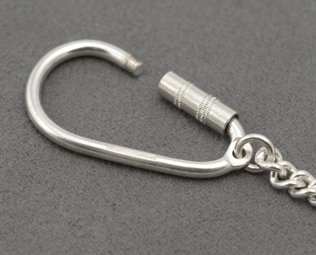 Silver key holder with the screw barrel undone, showing the threaded opening for adding keys