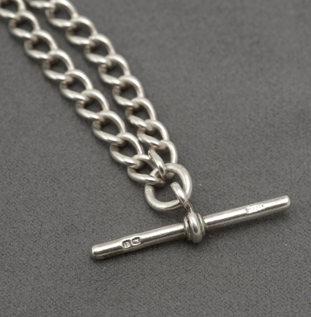 Silver double Albert watch chain laid out to show both graduated curb link sections, T bar and dog clips