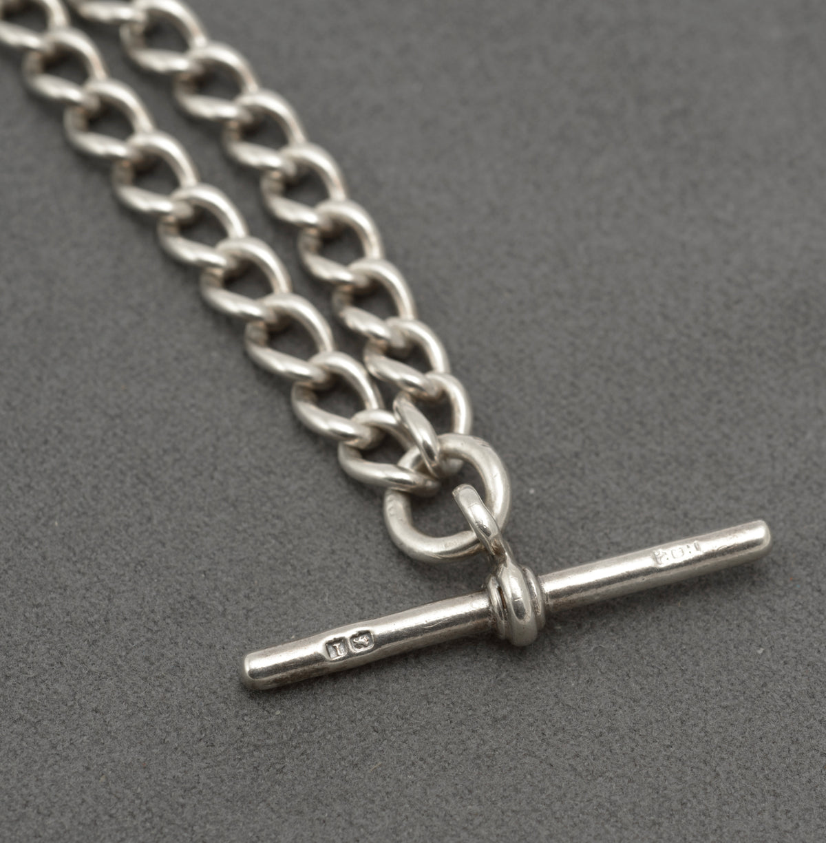 Silver double Albert watch chain laid out to show both graduated curb link sections, T bar and dog clips