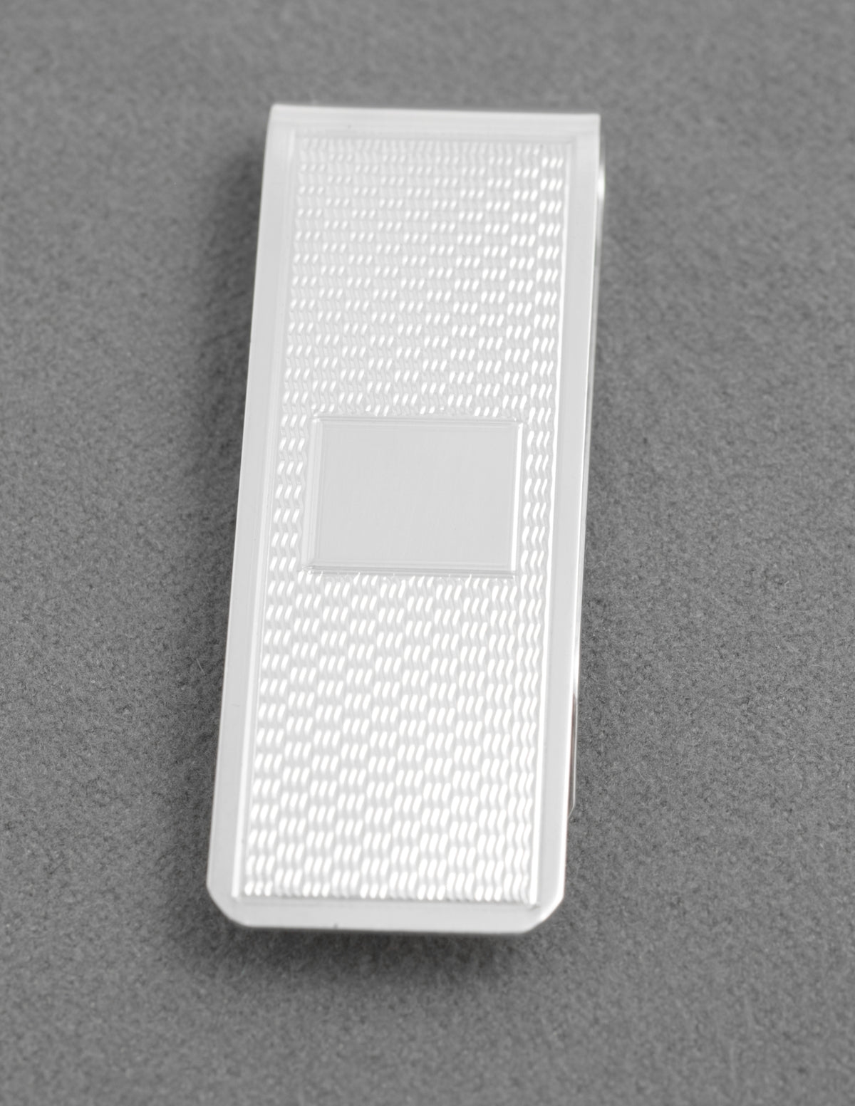 Angled view of the folded silver money clip and engine turned decoration