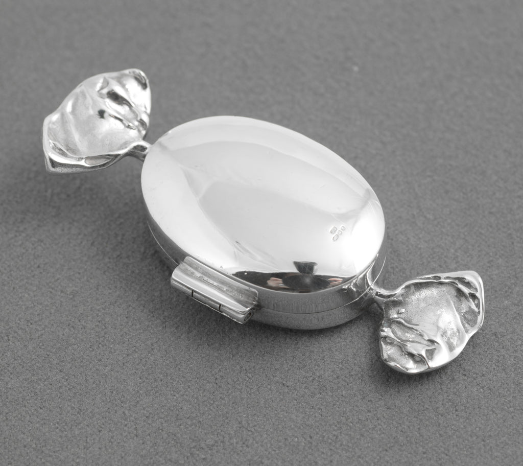 Side view of the silver sweet box showing its hinged oval centre