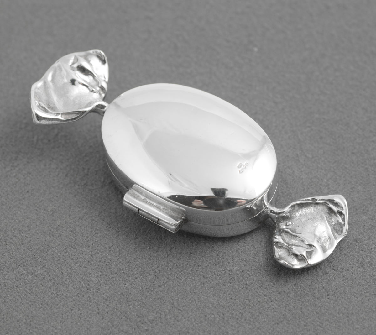 Side view of the silver sweet box showing its hinged oval centre