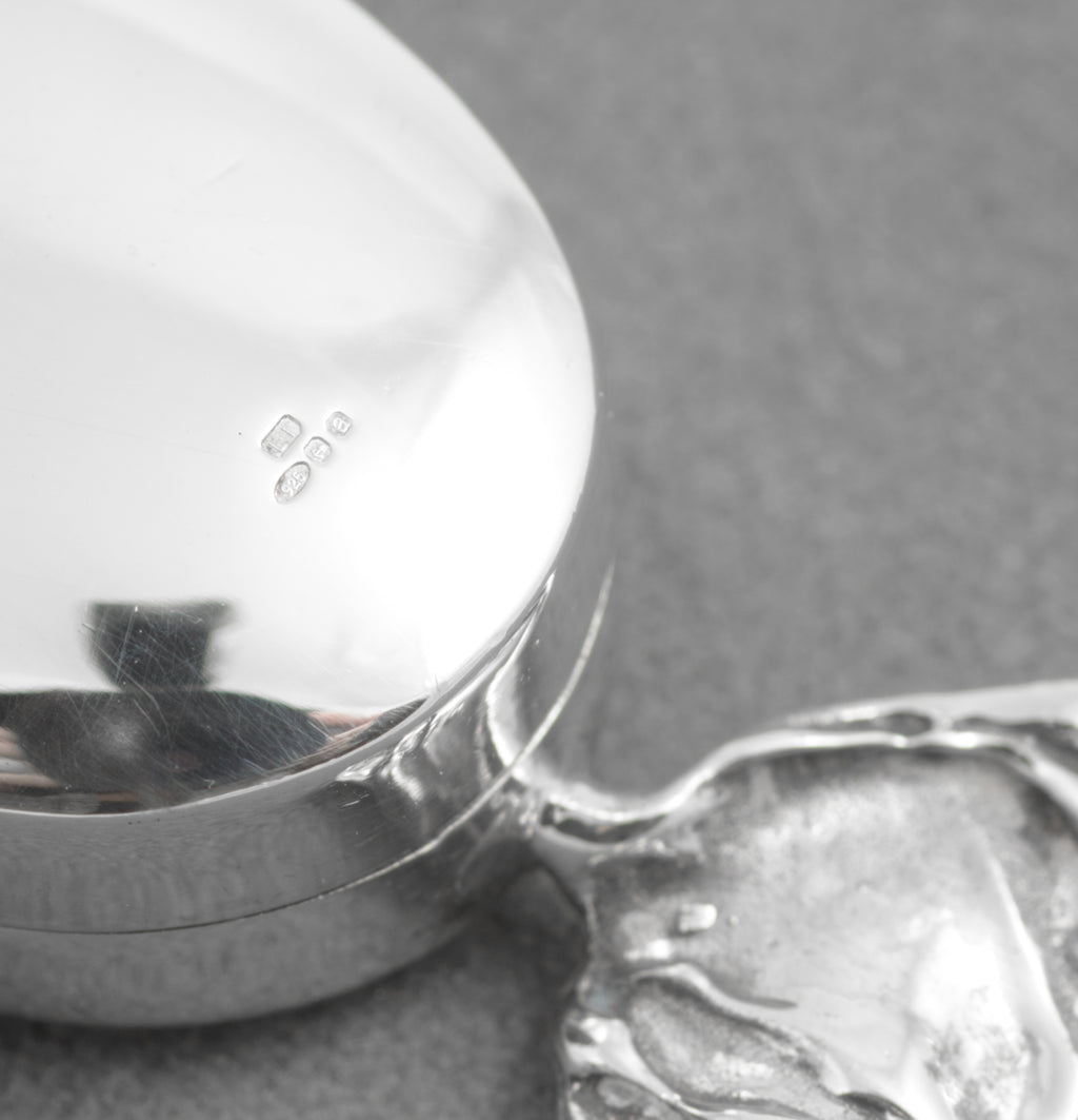 Silver sweet shaped pill box beside a British coin for scale