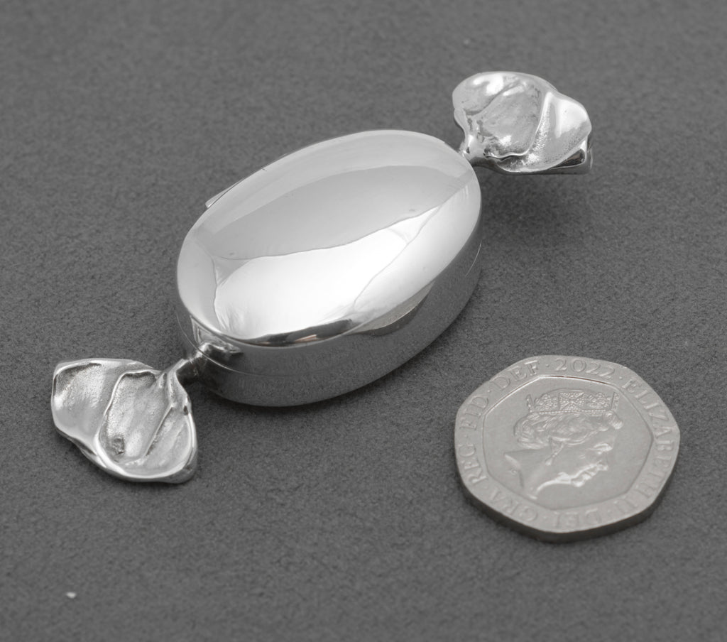 Polished oval lid and folded wrapper ends of the silver trinket box
