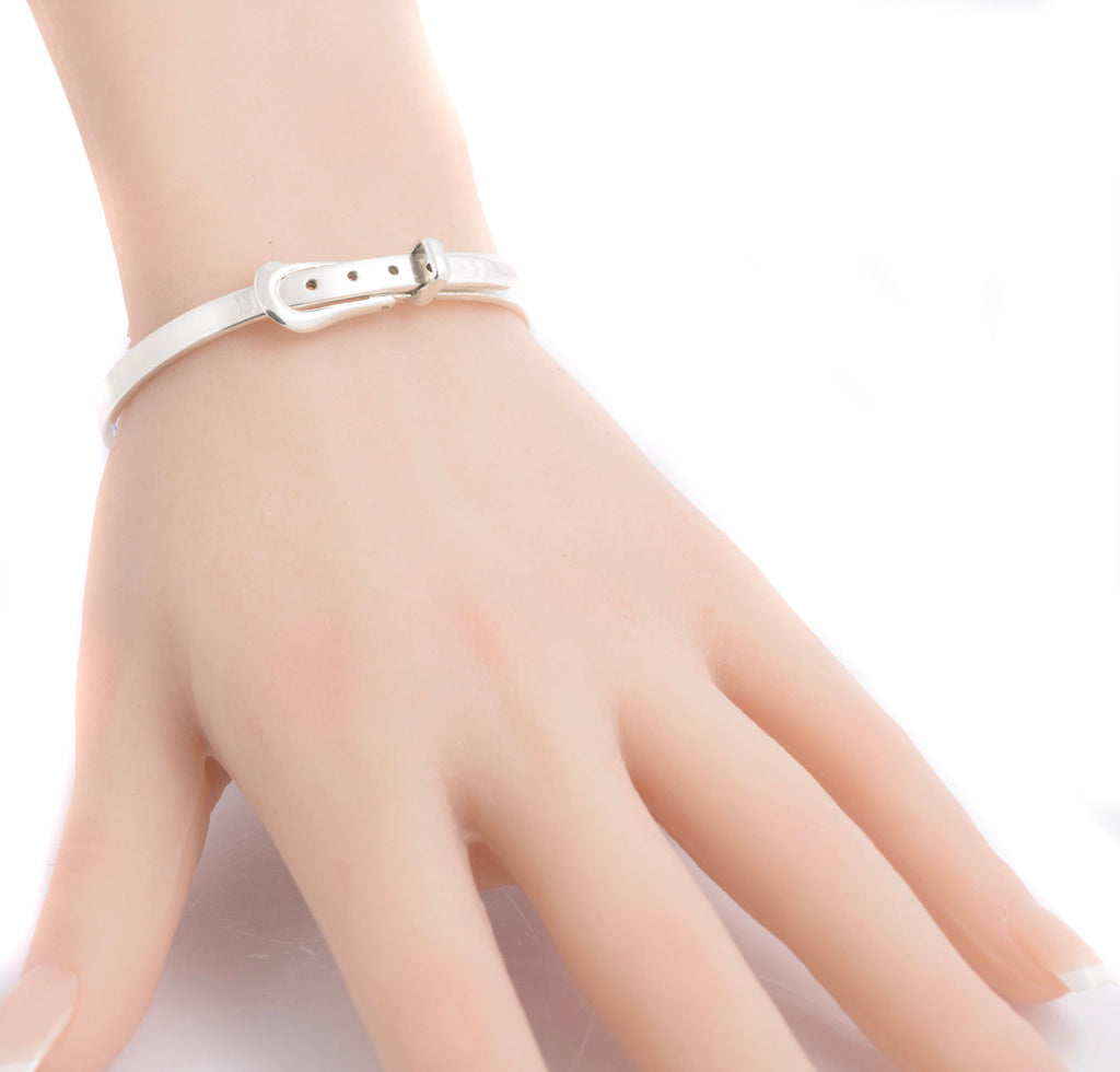Close view of the silver belt bangle and buckle on a model wrist