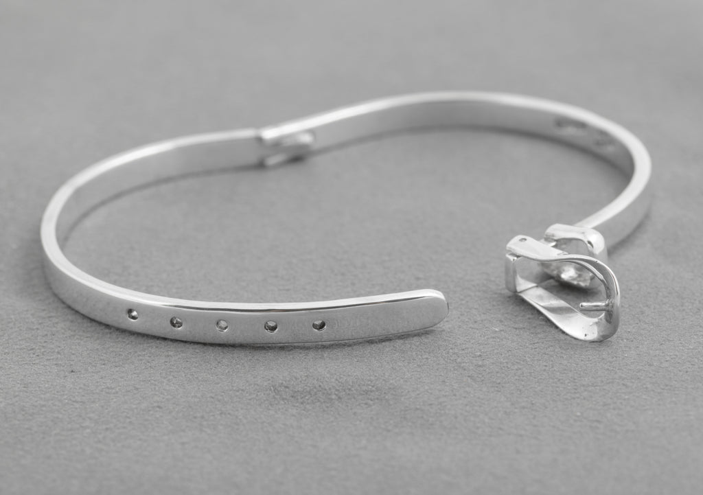 Close view of the open hinged buckle and five holes on the silver bangle