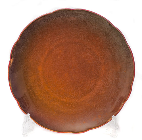 A round ceramic art pottery plate with a red flambe and crystalline glaze effect, featuring the signature of the artist 'Bernard Moore' on the reverse.
